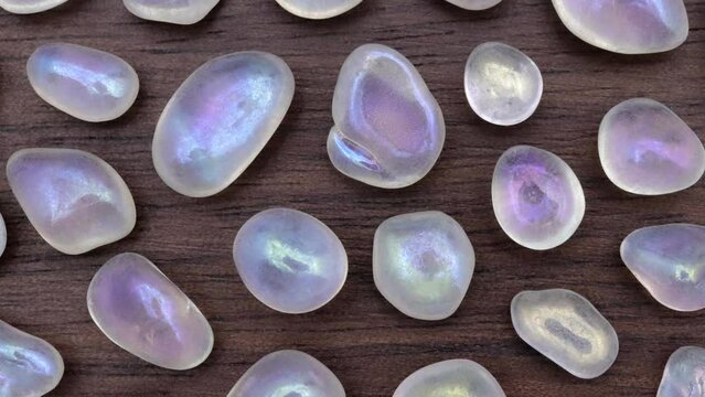 Shimmerstone rare jewel stones texture on brown varnished wood background. Moving right seamless loop backdrop.