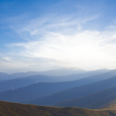 Fototapeta na wymiar mountain chain silhouette in blue mist at the sunset, early morning mountain travel scene