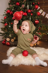 Cute little baby against blurred lights on dark background. Christmas celebration