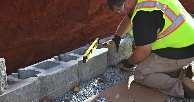 Contractor is induring the installation process of installing large block retaining wall constructed on construction site