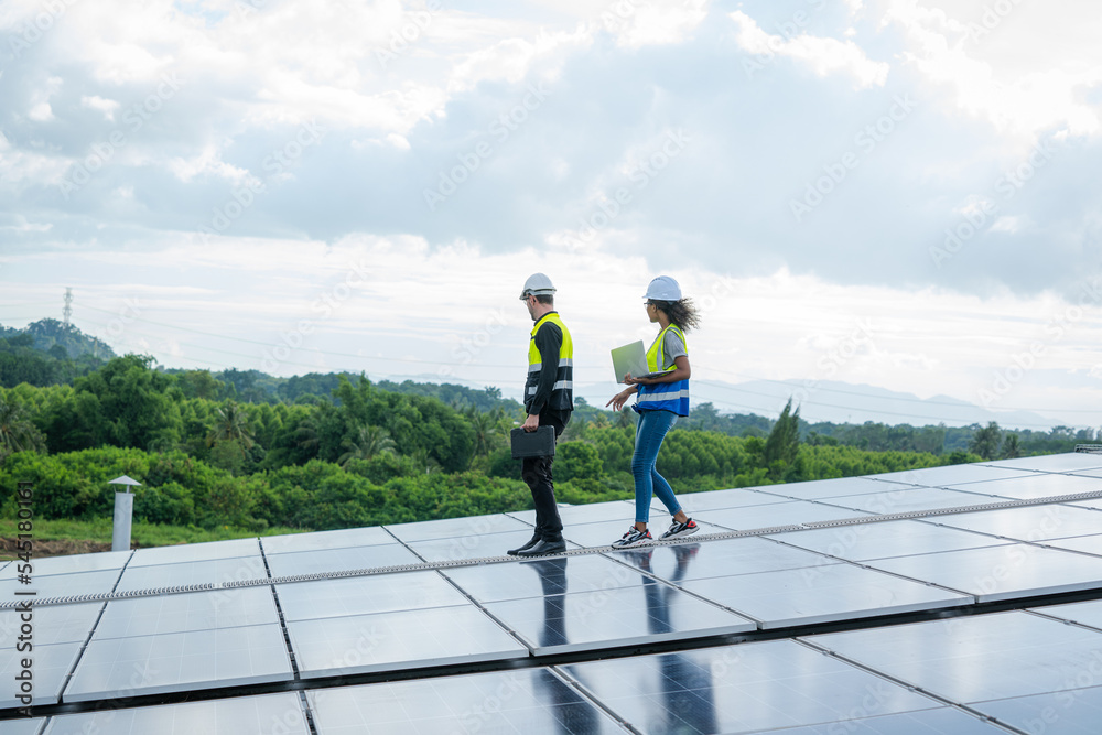 Poster technician wearing safety harness belt during installing the solar panels on roof structure of build