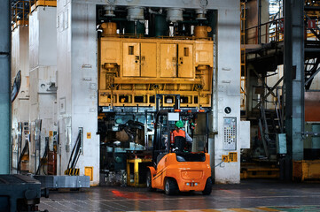 Giant stamping press. Sheet metal stamping. Electric forklift brings a pack of metal to work the...