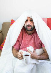 Hombre enfermo de gripe y coronavirus tapado con la manta