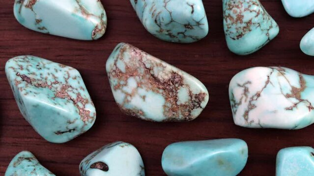 Turquoise rare jewel stones texture on brown varnished wood background. Moving right seamless loop backdrop.