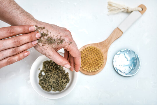 Young woman's hands apply massaging moves homemade cosmetic scrub of fresh ground mint, sugar and coconut oil