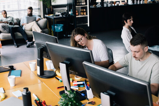 Female and male programmers coding on computers while working in startup company