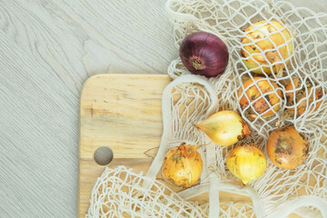 Various farm organic onions on a white wooden background. Zero waste shopping. Top view. Copy space.