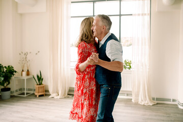 Side view of smiling senior man holding hand of woman while dancing in class