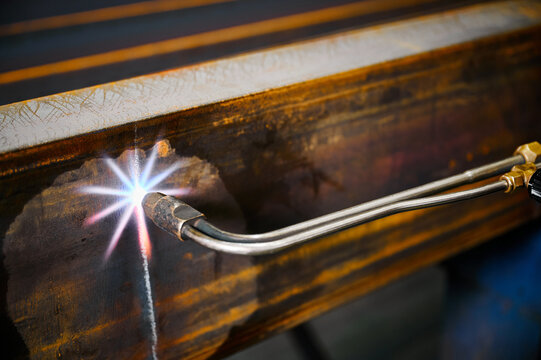 Cutting metal beam with oxy fuel cutter in plant workshop
