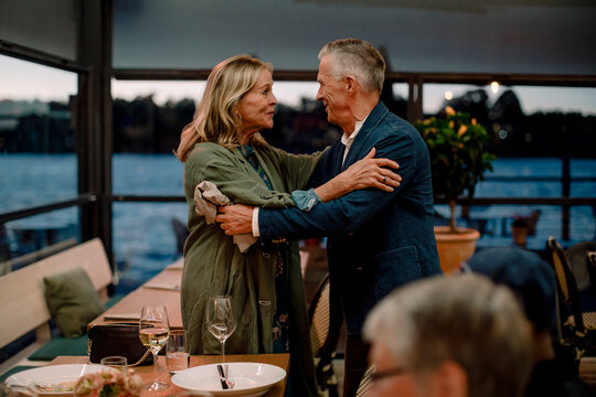 Smiling senior couple greeting each other in restaurant