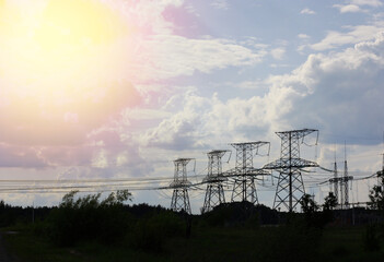 The power poles are located among a green field, against a blue sky with white clouds. High quality photo