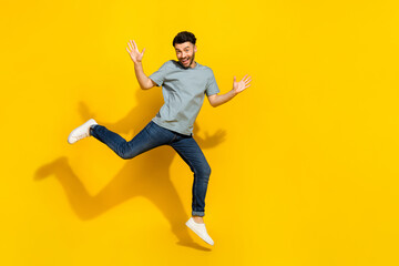 Full body portrait of satisfied glad person jumping raise hands empty space isolated on yellow color background