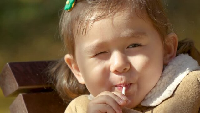 Little Girl Eating Lollipop in a Park - Face Close-up