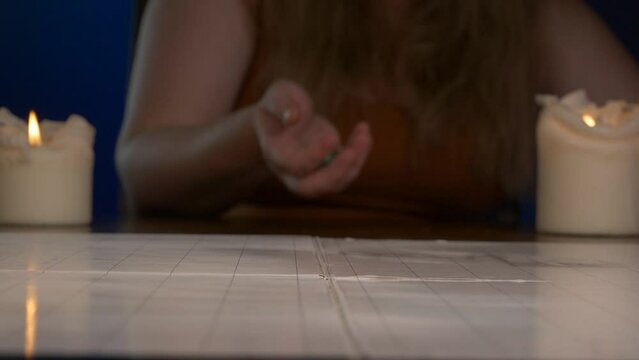 Woman Rolls Green Twenty Sided Die Across Game Table with Candles Lit