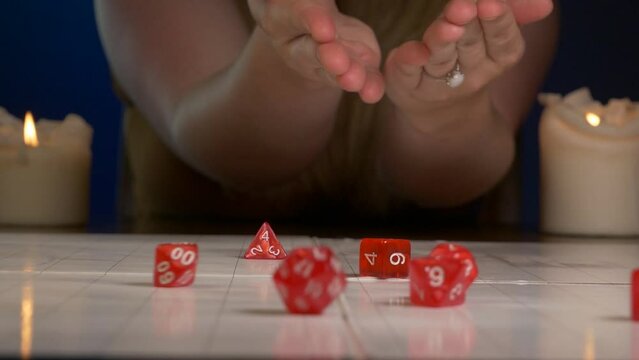 Woman Rolls Red RPG Dice Across Game Mat with Candles Lit