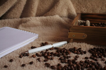 Fototapeta na wymiar The pen is on the table. Coffee, a wooden tray of cinnamon, and a candle are strewn nearby. Morning. Postcard for the inscription of wishes.