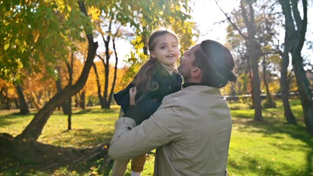 Happy family in an autumn park. Father took his daughter in his arms and kissed her. Slow motion