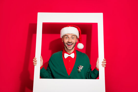 Photo of charming excited guy dressed xmas green cardigan tacking photo white photo frame isolated red color background