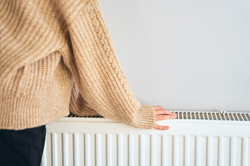 Kid freezing. Central heating problem. Checking heating radiator in cold apartment. Two hands in...
