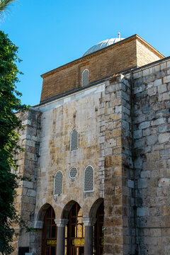 Perspective view of the entrance and dome of the Isa Bey Mosque, stone and brick facade. 