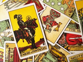 Picture of the Knight of Pentacles tarot card from the original Rider Waite tarot deck with mixed tarot cards in the background