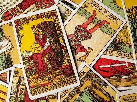 Picture of the Queen of Pentacles tarot card from the original Rider Waite tarot deck with mixed tarot cards in the background