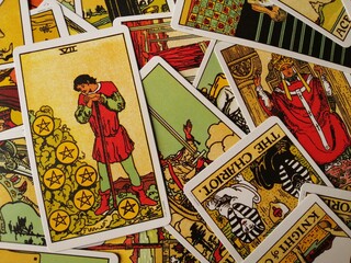 Picture of the Seven of Pentacles tarot card from the original Rider Waite tarot deck with mixed tarot cards in the background