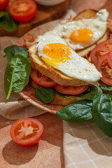 Homemade sandwiches with cheese sauce, spinach, tomatoes and fried eggs. Close up