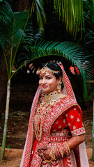 Portrait of a beautiful Indian bride in a traditional wedding dress. Young Hindu woman with golden Kundan jewelry set. Traditional Indian costume lehenga choli.  kalira and red nail paint
