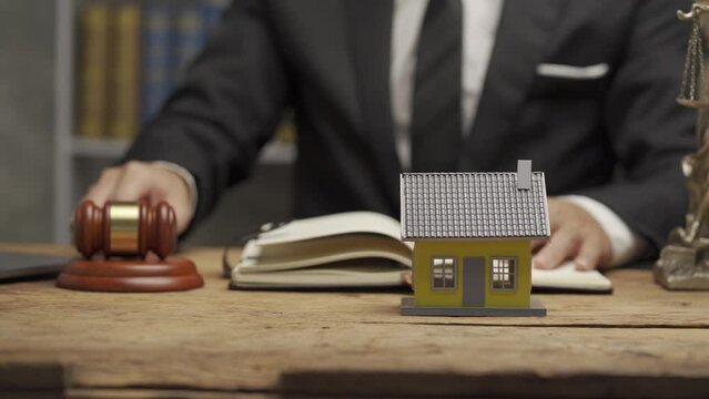 house auction idea, businessman holding a hammer and a house next to it Close-up of lawyer hand holding real estate hammer house and building idea at the office.