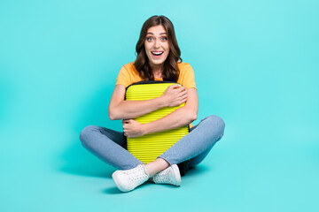 Full length photo of funky impressed lady wear yellow t-shirt embracing suitcase isolated turquoise color background