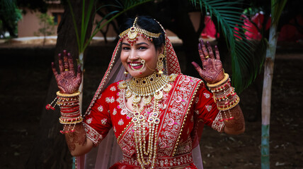 Portrait of a beautiful Indian bride in a traditional wedding dress. Young Hindu woman with golden...