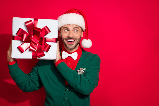 Photo of charming excited guy dressed xmas green cardigan bowtie listening inside noel gift empty space isolated red color background