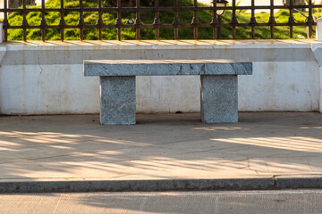 An empty stone bench with no people on a sidewalk at the tourist promenade in Pondicherry.