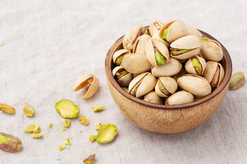 Pistachio in wooden bowl on linen table cloth background