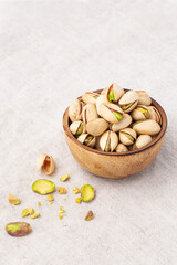 Pistachio in wooden bowl on linen table cloth background