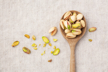 Pistachio in wooden spoon on linen table cloth background