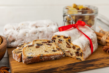 Christmas stollen is a traditional german bread on a white wooden table. Festive dessert made of dough, nuts and marzipans sprinkled with powdered sugar.Copy space. Place for text.