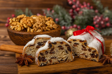 Christmas stollen - traditional German bread on a brown wooden table with fir branches. Festive dessert made of dough, nuts and marzipans sprinkled with powdered sugar.Copy space. Place for text.