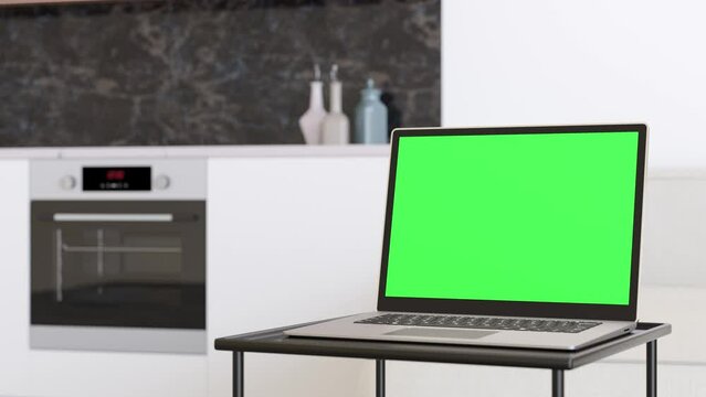 Laptop with blank green screen, standing on table at home. Computer mock up with Chroma Key. Copy space for video, app, game, website presentation. Empty laptop screen. Modern interior. 3D animation.