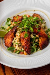 Wonderful shot of yummy grilled pieces of pork served on a white plate with corn and vegetables