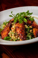 Wonderful shot of yummy grilled pieces of pork served on a white plate with corn and vegetables