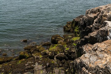 High-angle of mossy rocky cliffs  near the ocean, water waves background