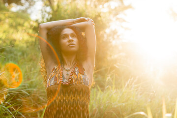 Imagen horizontal de una mujer latina al aire libre conectando con la madre naturaleza mientras...