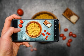 Top view closeup of a smartphone taking a photo of pasta ingredients on the table