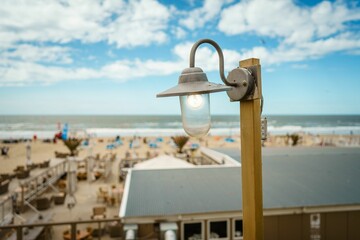 Closeup of a vintage street lamp in a beautiful crowded beach against a blue sky