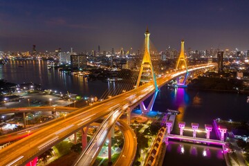 Fototapeta na wymiar Scenic bird's eye view of an elevated suspension bridge above a river in Bangkok during nighttime