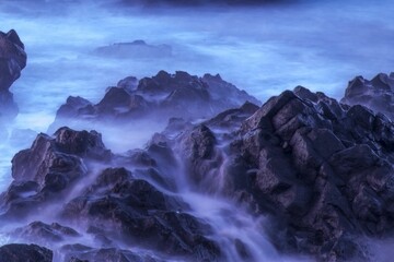 Long exposure of fog, mist on rocks, a purple background