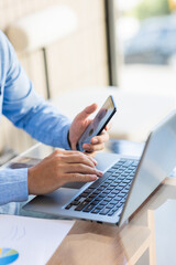 Fototapeta premium Asian businessmen use equipment for business. Holding a smartphone that works with laptops and mobile phones, showing statistics and software apps.