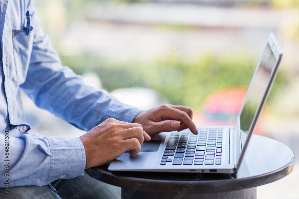 Wall mural Side view of male businessman hands typing on laptop keyboard.